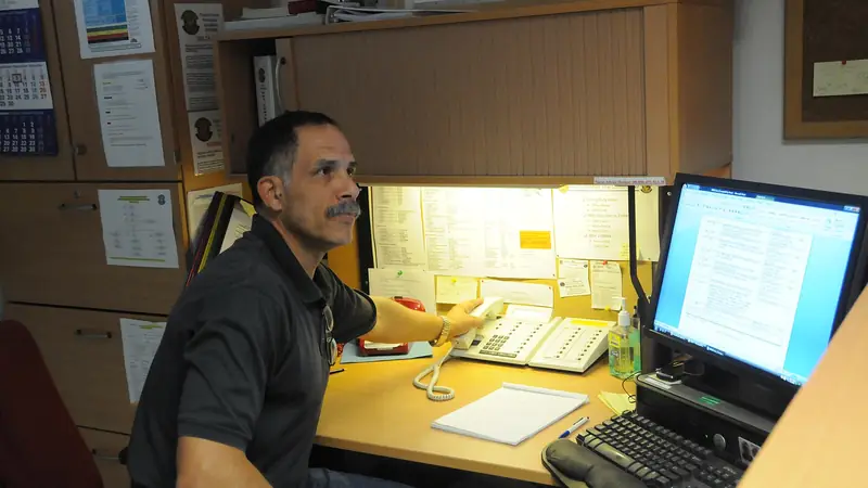 An office worker at his desk, checking records on a computer screen