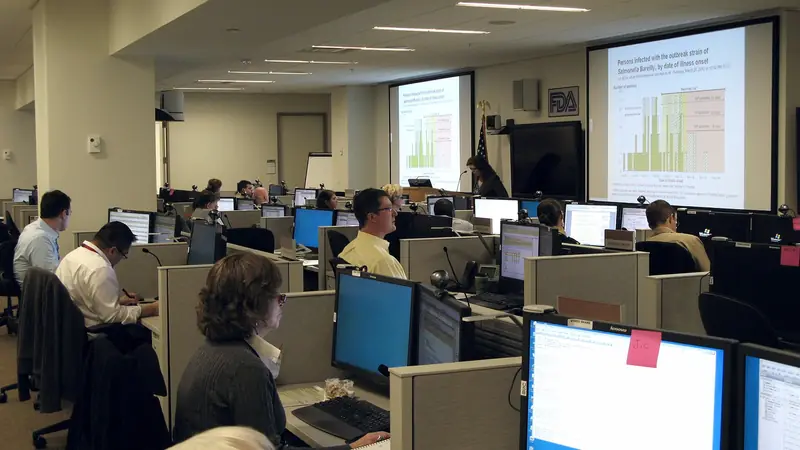 An emergency operations centre with staff at workstations and data on large screens
