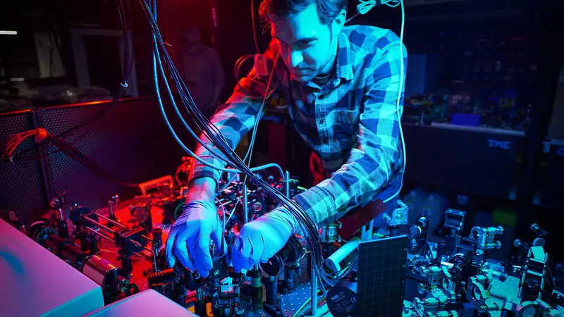 A scientist adjusting optical equipment for quantum research in a laboratory