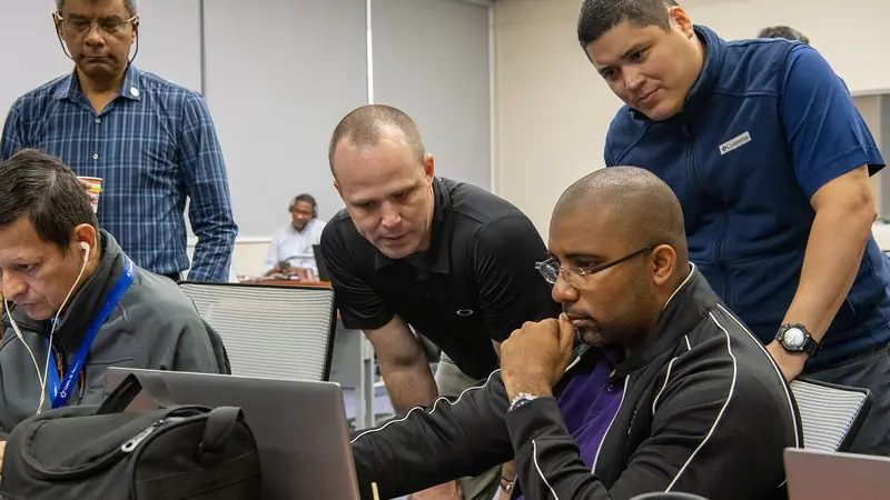 A team gathered around a laptop working through a cyber security exercise