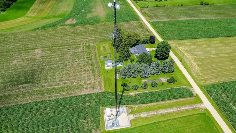 Aerial view of a mobile network tower among green farm fields
